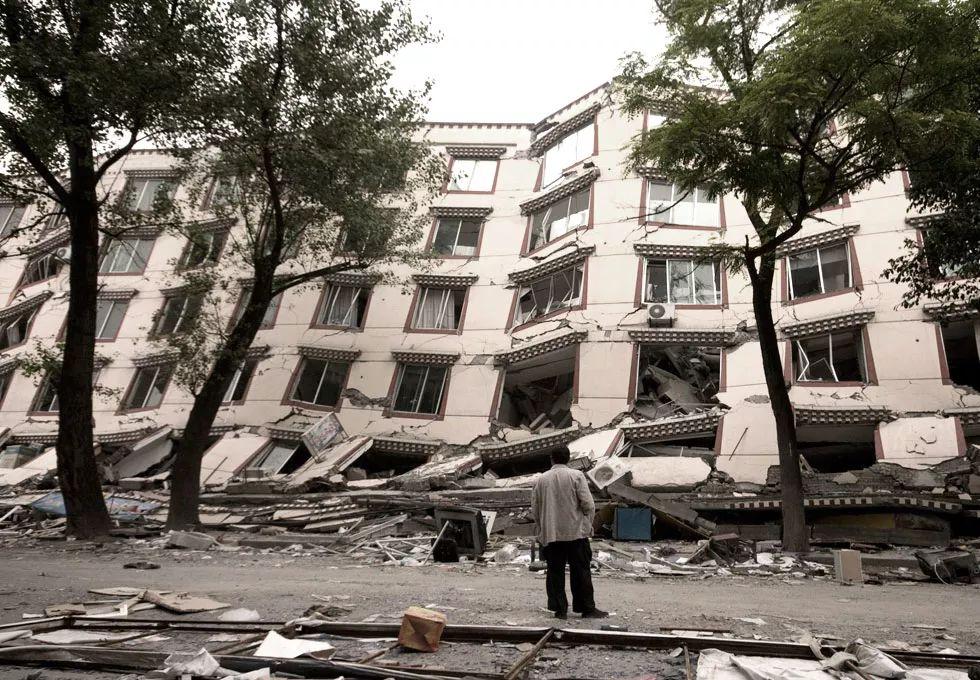 2008年5月20日,四川映秀,一男子在看一幢被地震严重摧毁的房子.